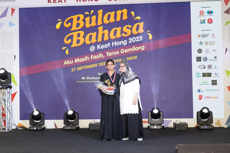Pelajar Menengah 1, Sekolah Menengah Chua Chu Kang, Daania Eiliyah Akbar Ali (kiri), bergambar bersama Pengerusi Jawatankuasa Eksekutif Kegiatan Melayu (MAEC) Kelab Masyarakat (CC) Keat Hong, Cik Jurainah Yusof, setelah dinobat juara peraduan, ‘Petah Spontan 2025’, di Kelab Masyarakat Keat Hong, pada 27 September.
