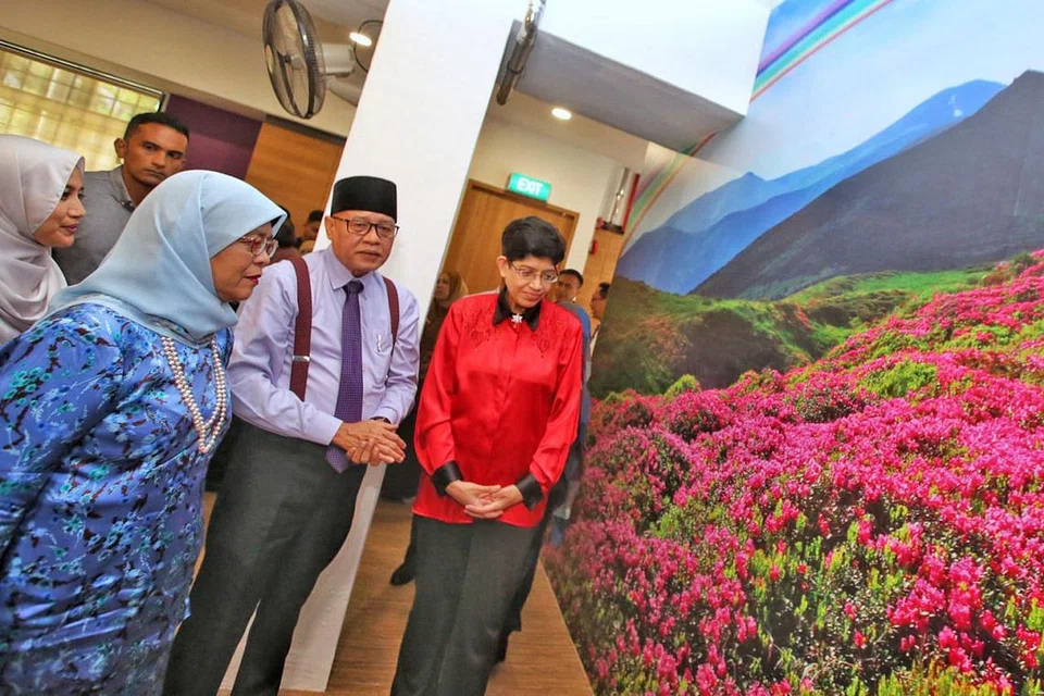 TINJAU KEMUDAHAN: Presiden Halimah mendengar taklimat CEO Persatuan Ain, Encik Md Yusof (tengah), mengenai tarikan baru pusat barah kedua persatuan itu, disertai AP GRC Marine Parade Dr Fatimah (kanan). - Foto CMG