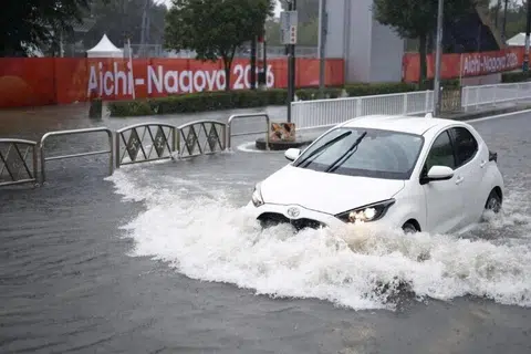 Sebuah kereta meredah jalan yang dinaiki air akibat hujan lebat, dengan sepanduk Sukan Asia Aichi-Nagoya kelihatan di Nagoya pada 8 September. Hujan lebat itu turut memaksa ratusan atlet dan pegawai Sukan Asia berpindah sementara dari tempat penginapan mereka, dengan beberapa  lokasi pertandingan dimasuki air.
