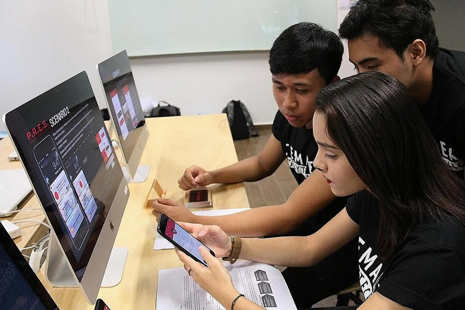 PENGALAMAN BARU: (Dari kiri) Encik Luqman, Encik Mohamad Asyraaf dan Cik Nurrisha berpeluang membangun prototaip aplikasi kiriman isyarat kecemasan yang dijana bersama pakar teknologi kreatif DDB Worldwide Singapore. - Foto SHAKIR SAIFUDDIN