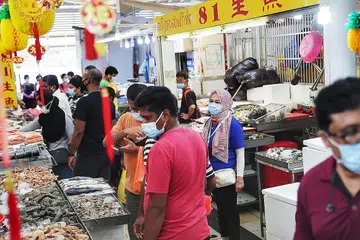 LEBIH TERKAWAL: Kakitangan jarak selamat (berbaju biru) bertugas di pasar Tekka bagi memastikan langkah-langkah keselamatan diawasi semalam dengan jumlah pengunjung dijangka bertambah semasa tempoh menjelang Raya. - Foto BH oleh KELVIN CHNG