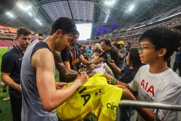 BERAMAH MESRA: Bintang Tottenham Hotspur, Son Heung-min, menandatangani baju seorang peminat selepas satu sesi latihan di Stadium Nasional pada Selasa.