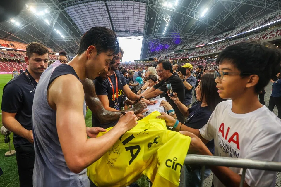 BERAMAH MESRA: Bintang Tottenham Hotspur, Son Heung-min, menandatangani baju seorang peminat selepas satu sesi latihan di Stadium Nasional pada Selasa.