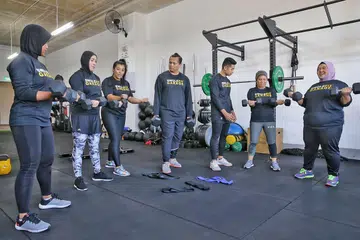 DITUNJUK AJAR JURULATIH BERTAULIAH: (Dari kiri) Cik Raba'a Mohd Jamil, 33 tahun; Cik Lynn Siregar; jurulatih Suganthi Mani Maran; Encik Mohammad Fadli, 39 tahun; jurulatih Mohd Sarhan Hamed, Cik Norizan Mohd Yusuf; dan Cik Farah Umainah Jumani bersenam menggunakan dumbel di Swolefit Garage. - Foto BH oleh KEVIN LIM