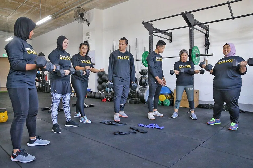 DITUNJUK AJAR JURULATIH BERTAULIAH: (Dari kiri) Cik Raba'a Mohd Jamil, 33 tahun; Cik Lynn Siregar; jurulatih Suganthi Mani Maran; Encik Mohammad Fadli, 39 tahun; jurulatih Mohd Sarhan Hamed, Cik Norizan Mohd Yusuf; dan Cik Farah Umainah Jumani bersenam menggunakan dumbel di Swolefit Garage. - Foto BH oleh KEVIN LIM