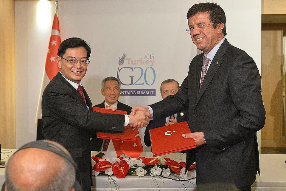 CAPAI PERSETUJUAN: Encik Heng berjabat tangan dengan rakan sejawatannya dari Turkey, Encik Nihat Zeybekci, semasa menemani Perdana Menteri Lee Hsien Loong ke Sidang Puncak Kumpulan 20 (G20) di Turkey pada 2015. - Foto fail 