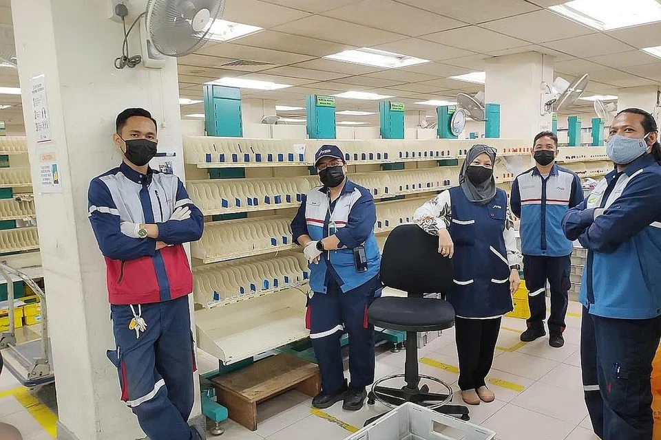 RAPAT BERSAMA RAKAN KERJA: (Paling kanan) Encik Haslan, (tiga dari kanan) Cik Siti Sarah, (empat dari kanan) Cik Surati, bergambar bersama rakan kerja mereka di SingPost yang merupakan warga Malaysia,(paling kiri) Encik Muhammad Syakir Azman dan Encik Khairul Nazmi Othman. - Foto SINGPOST