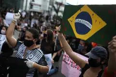 TUNJUK PERASAAN: Seorang penunjuk perasaan anti-pemerintah di Manaus, Brazil, dilihat memakai pelitup kerana penularan penyakit koronavirus (Covid-19) memegang sepanduk bendera Brazil dengan mesej "Black Lives Matter" sebagai membantah tindakan polis Amerika Syarikat yang membawa kematian seorang warga negara itu yang berkulit hitam, Encik George Floyd, semasa dalam tahanan polis pada 25 Mei lalu.