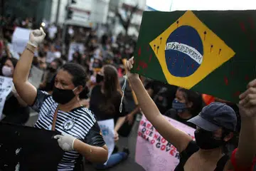 TUNJUK PERASAAN: Seorang penunjuk perasaan anti-pemerintah di Manaus, Brazil, dilihat memakai pelitup kerana penularan penyakit koronavirus (Covid-19) memegang sepanduk bendera Brazil dengan mesej "Black Lives Matter" sebagai membantah tindakan polis Amerika Syarikat yang membawa kematian seorang warga negara itu yang berkulit hitam, Encik George Floyd, semasa dalam tahanan polis pada 25 Mei lalu.