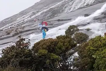 DETIK NGERI: Beberapa pendaki dan malim gunung kelihatan merenggangkan tali semasa menyeberang satu kawasan di puncak gunung yang ditimpa air deras pada awal pagi 12 September.