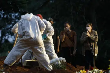 KORBAN COVID-19: Gambar yang dirakamkan pada 17 April 2021 ini menunjukkan sekumpulan orang hiba melihat pengebumian saudara mereka yang dilakukan kakitangan di pusara yang memakai alat pelindung peribadi sebagai langkah pencegahan bagi mengekang penularan Covid-19, di Tanah Perkuburan Vila Formosa, di Sao Paola, Brazil. - Foto 