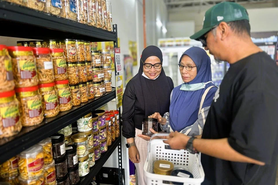 Cik Rahana Worie (kiri), bersama ahli keluarganya memilih kuih Raya yang hendak dibawa pulang ke Singapura.