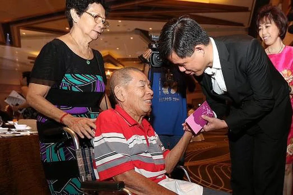 BERI HABUAN: Encik Chan memberi hong bao kepada mantan ketua jurutera marin dan anggota SMOU, Encik Leo Boon Hui (duduk), yang ditemani isterinya, Cik Dan Wah Eng (kiri), di majlis semalam. - Foto THE STRAITS TIMES
