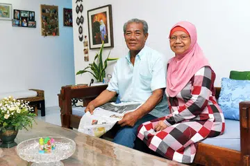 MANFAATKAN LBS: Encik Mohd Adefar Kassim dan isterinya Cik Kalsom Makmoer selesa tinggal di rumah mereka di Segar Road dan tidak berhasrat berpindah. Mereka yang tinggal di flat empat bilik ini lebih 15 tahun telah memanfaatkan Skim Beli Balik Pajakan (LBS) yang ditawarkan HDB. - Foto fail