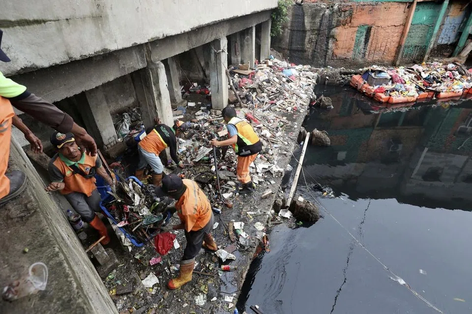 BERSIHKAN SELEPAS BANJIR: Beberapa pekerja mengumpul dan membersihkan sampah yang bertaburan selepas berlaku banjir di Jakarta pada awal tahun baru. - Foto AP