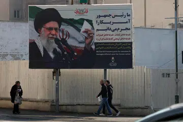 Penduduk Iran berjalan melepasi papan iklan yang memaparkan gambar Pemimpin Tertinggi Iran, Ayatollah Ali Khamenei, berserta ayat dalam bahasa Parsi yang berbunyi “Kami mengenali Presiden Amerika Syarikat sebagai penjenayah” susulan protes anti-pemerintah, di sebuah jalan di Teheran, Iran, pada 24 Januari 2026. Presiden Amerika Syarikat, Donald Trump, memperbaharui ancaman tindakan ketenteraan terhadap Iran susulan gelombang protes anti-pemerintah ketika negara itu mengalami gangguan internet di seluruh negara yang bermula pada 8 Januari 2026. 