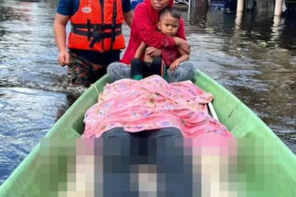 DETIK PALING SEDIH: Seorang suri rumah, Cik Norzubaila Ramli, 36 tahun, menarik sendiri mayat suaminya sejauh kira-kira 100 meter hingga ke rumah, selepas lelaki itu ditemui lemas dalam banjir dipercayai akibat terjatuh dari perahu di Kampung Bakat, Rantau Panjang, Kelantan, pada Isnin.