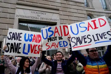  Orang ramai memegang plakad di bangunan  Agensi Pembangunan Antarabangsa Amerika Syarikat (USAID) yang ditutup kepada kakitangan selepas satu memo dikeluarkan yang menasihatkan pegawai agensi untuk bekerja dari rumah, di Washington, D.C., Amerika Syarikat, 3 Februari 2025.  