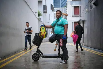 TABAH JALANKAN TUGAS: Bersyukur apabila ada pelanggan, yang melihat keadaan beliau apabila tiba di pintu rumah dengan bertongkat, memberinya tip, minuman dan kata-kata perangsang. - Foto BM oleh MARK CHEONG