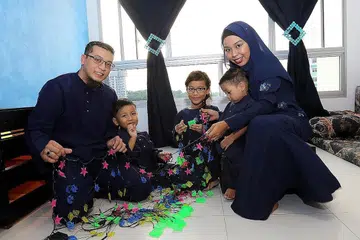 MENGHIAS RUMAH: Encik Nasrullah dan Cik Marzaliza pertama kali dalam masa lima tahun menghias rumah sendiri untuk Hari Raya bersama tiga anak mereka. - Foto SHAHRIYA YAHAYA