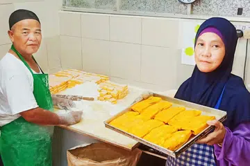 KARIPAP 'BAI' RESIPI ASLI: Encik Ismail dibantu isterinya, Cik Hamidah, di gerai yang menjual khusus karipap 'bai' di Pusat Penjaja Circuit Road. - Foto BM oleh SAINI SALLEH.