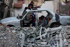Kanak-kanak berkumpul dalam kenderaan yang musnah di tengah-tengah konflik Israel-Hamas di Khan Younis di selatan Jaluran Gaza pada Oktober 2024.