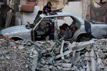 Kanak-kanak berkumpul dalam kenderaan yang musnah di tengah-tengah konflik Israel-Hamas di Khan Younis di selatan Jaluran Gaza pada Oktober 2024.