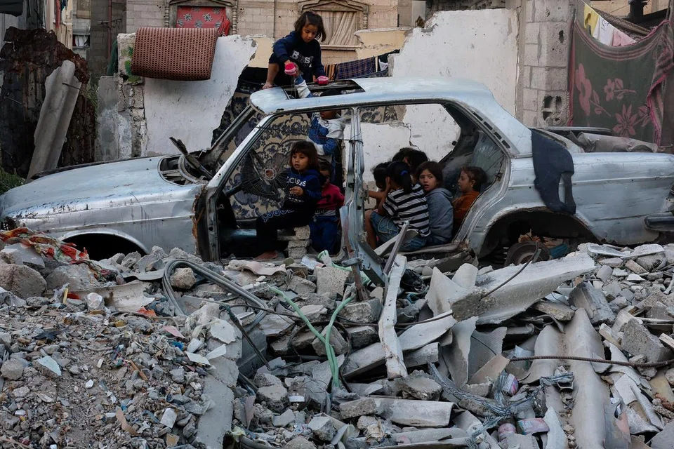 Kanak-kanak berkumpul dalam kenderaan yang musnah di tengah-tengah konflik Israel-Hamas di Khan Younis di selatan Jaluran Gaza pada Oktober 2024.