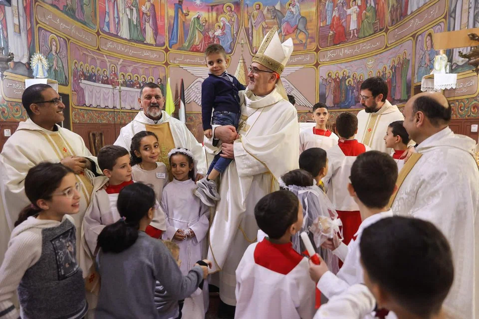 Ketua Biskop, Pierbattista Pizzaballa (tengah), bergambar dengan orang ramai dan kanak-kanak di Gereja Holy Family di kejiranan al-Zaytoun, Bandar Gaza, pada 22 Disember. 