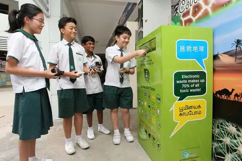 KITAR SEMULA: Para pelajar membuang barangan elektronik yang tidak digunakan lagi ke dalam tong kitar semula yang disediakan di bawah Program 'RENEW' StarHub. - Foto fail