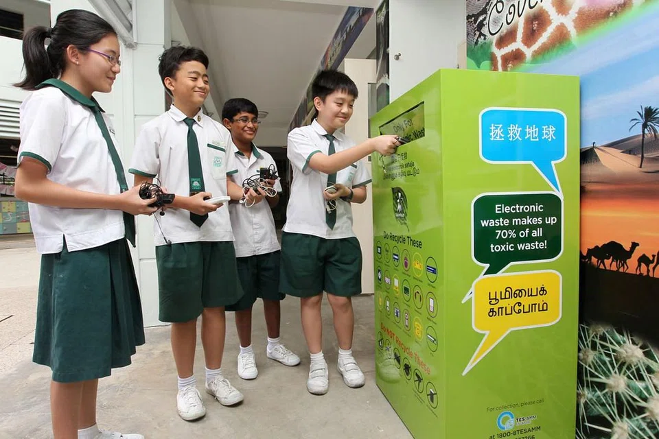 KITAR SEMULA: Para pelajar membuang barangan elektronik yang tidak digunakan lagi ke dalam tong kitar semula yang disediakan di bawah Program 'RENEW' StarHub. - Foto fail