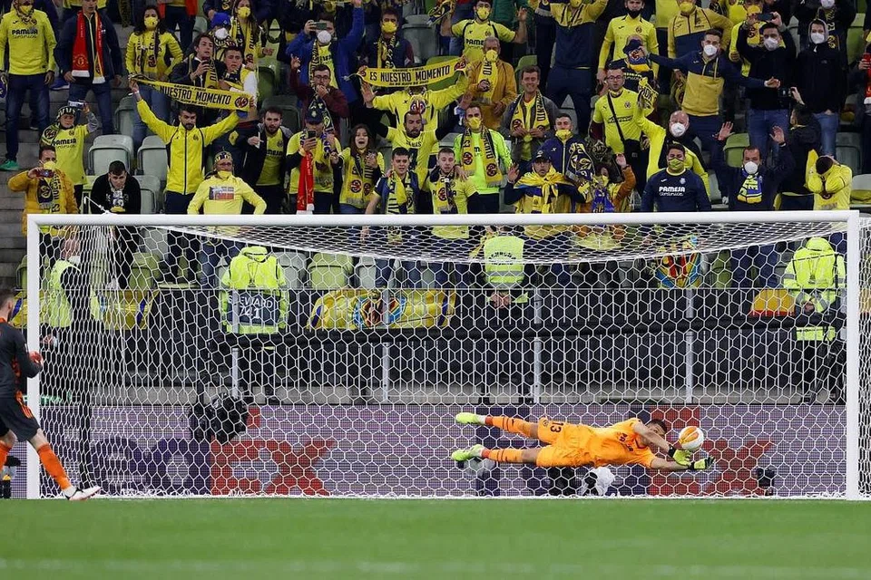 DIKECEWAKAN: Penjaga gol Villarreal Geronimo Rulli menyelamatkan sepakan penalti penjaga gawang Manchester United David de Gea. - Foto REUTERS
