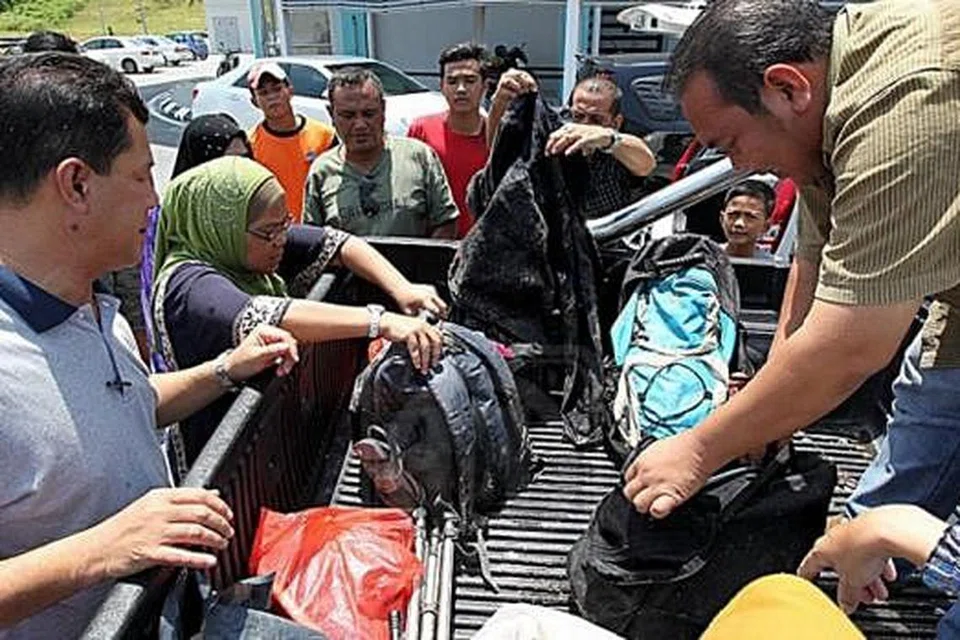 BAWA PULANG BARANGAN MANGSA: Saudara-mara empat sahabat karib yang ditemui maut di dasar sungai mengambil barangan mangsa yang ditemui di tempat kejadian. - Foto UTUSAN MALAYSIA