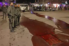 DESAK TEBUSAN DIBEBAS: Para pegawai keselamatan melihat cat merah sebagai simbol darah tebusan yang dituang di permukaan jalan raya oleh peserta protes dekat kediaman Perdana Menteri Israel di Baitulmakdis pada 22 Januari.