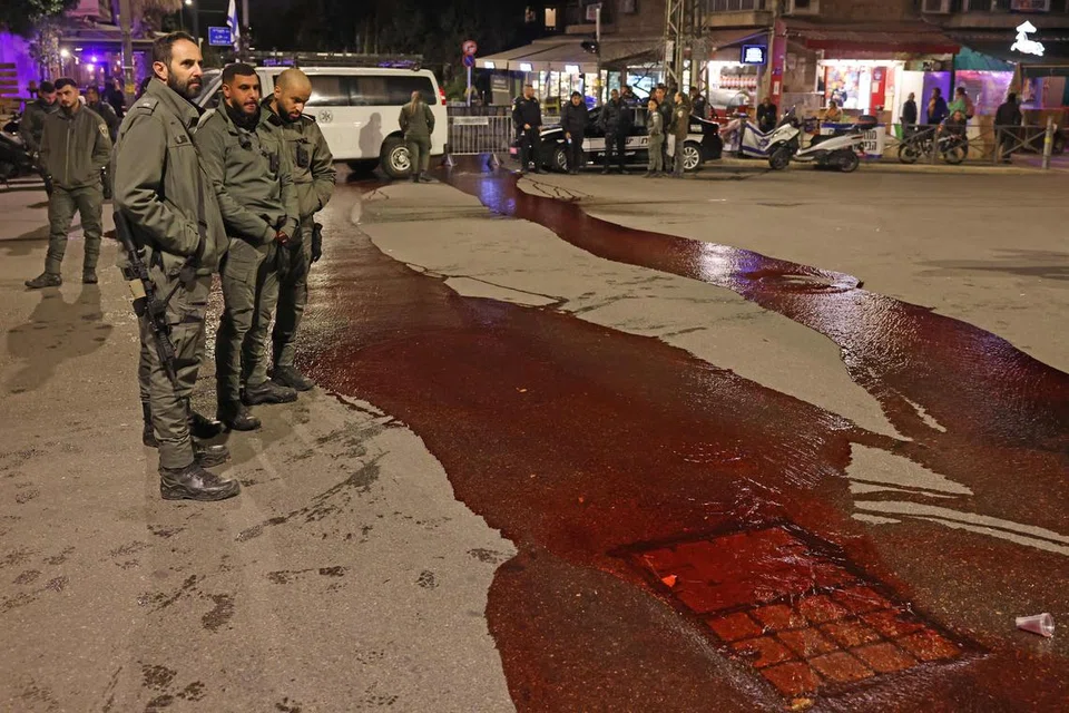 DESAK TEBUSAN DIBEBAS: Para pegawai keselamatan melihat cat merah sebagai simbol darah tebusan yang dituang di permukaan jalan raya oleh peserta protes dekat kediaman Perdana Menteri Israel di Baitulmakdis pada 22 Januari.