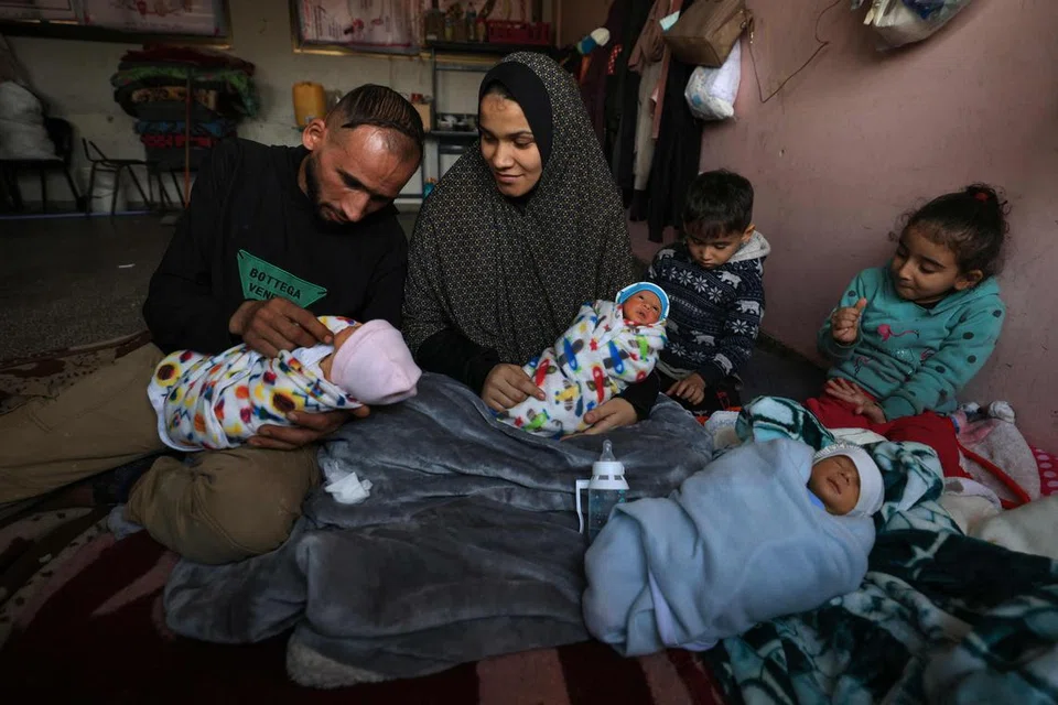 KEHIDUPAN PENUH MENCABAR: Encik  Ammar dan isterinya, Cik Iman al-Masri, yang meninggalkan rumah mereka di Beit Hanoun untuk mengelak pengeboman tentera Israel, menimang tiga daripada kembar empat mereka di kem perlindungan di Deir al-Balah, di tengah Gaza.
