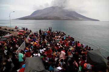 Sekitar 330 penduduk sedang dipindahkan dari Kabupaten Kepulauan Sitaro, Sulawesi Utara, di tengah-tengah letusan Gunung Ruang (latar belakang), meninggalkan Tagulandang pada 1 Mei 2024, ke Bitung dengan menaiki kapal KRI Kakap Angkatan Laut Indonesia. 