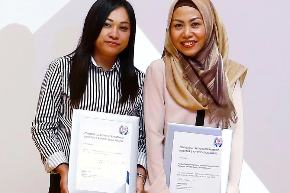 KHIDMAT CEMERLANG: Pegawai khidmat pelanggan Western Union Global Network cawangan Lucky Plaza, Cik Suhartini Sary (kiri), bersama penyelianya Cik Endah Wahyuningsih berjaya melindungi seorang pelanggan daripada menjadi mangsa penipuan penyaluran wang. Usaha mereka diiktiraf dalam Majlis Anugerah Penghargaan CAD di Kompleks Polis Cantonment semalam. - Foto SPF