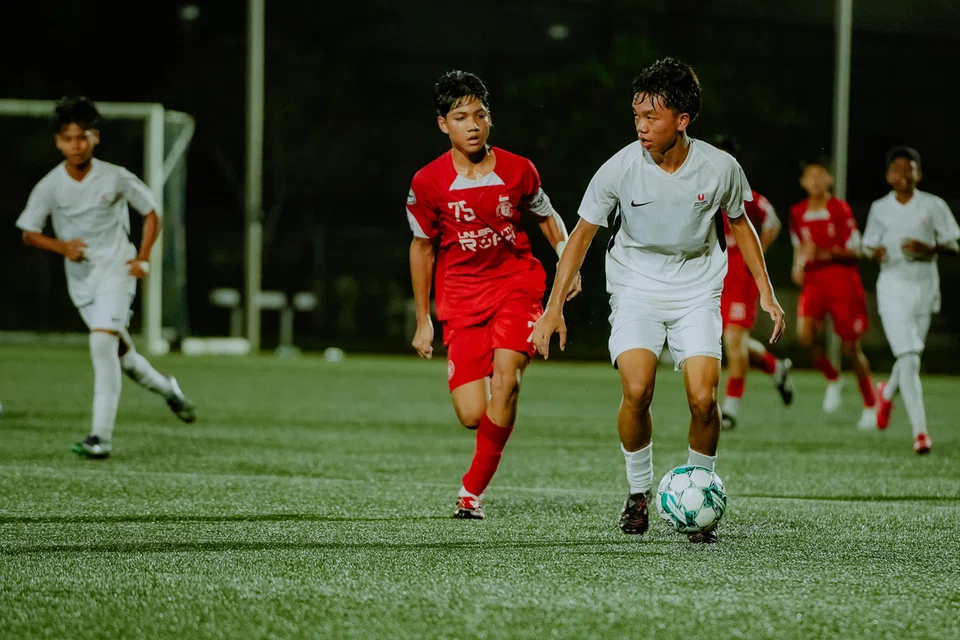 Walaupun dia menentang pemain yang setahun lebih tua daripadanya, penyerang Pusat Pembangunan Nasional (NDC), Ayden Naim Fakhry Fazrul Nawaz (tengah),  tidak gentar mengharungi cabaran tersebut bermain di Liga Belia Singapura (SYL).