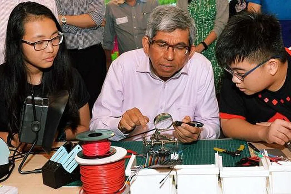 MENCUBA MEMATERI: Dr Yaacob Ibrahim (tengah) bersama pelajar yang menyertai pembukaan makmal IDA di Perpustakaan Daerah Jurong November lalu. - Foto fail