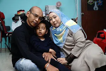 DAPATKAN RAWATAN DI LUAR NEGARA: Bergambar bersama ibu bapanya, Aryan menghidap sejenis barah di otaknya yang menjejas keupayaannya untuk bertutur, bergerak dan berjalan serta sering keletihan. - Foto BH oleh KHALID BABA
