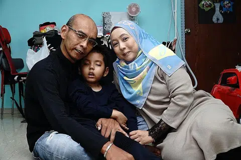 DAPATKAN RAWATAN DI LUAR NEGARA: Bergambar bersama ibu bapanya, Aryan menghidap sejenis barah di otaknya yang menjejas keupayaannya untuk bertutur, bergerak dan berjalan serta sering keletihan. - Foto BH oleh KHALID BABA
