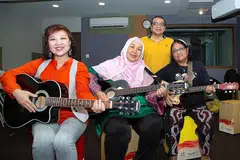 GIGIH ASAH KEMAHIRAN: (Dari kiri) Cik Susan Teo, Cik Siti Salmiah Junid dan Cik Nasmah Isnin tidak membiarkan usia 60-an tahun sebagai halangan mempelajari kemahiran memetik gitar dan bermain alat genderang 'cajon' daripada pemuzik, Moliano Rasmadi (belakang). - Foto BM oleh ZALEHA ABDUL KADER