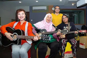 GIGIH ASAH KEMAHIRAN: (Dari kiri) Cik Susan Teo, Cik Siti Salmiah Junid dan Cik Nasmah Isnin tidak membiarkan usia 60-an tahun sebagai halangan mempelajari kemahiran memetik gitar dan bermain alat genderang 'cajon' daripada pemuzik, Moliano Rasmadi (belakang). - Foto BM oleh ZALEHA ABDUL KADER