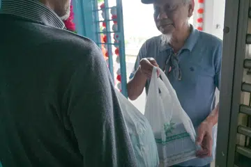 Sukarelawan (kanan) daripada Persatuan Muhammadiyah membantu mengagihkan makanan iftar/buka puasa pada bulan Ramadan 2025.  