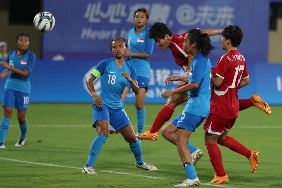 CUBA PERTAHANKAN: Pasukan bola sepak wanita Singapura (jersi biru) bergelut mempertahankan hantaran lintang dan sepakan penjuru dari skuad Korea Utara dalam perlawanan pembukaan Sukan Asia Hangzhou di Stadium Pusat Sukan Wenzhou pada Ahad. 