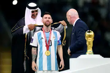 Emir Qatar, Sheikh Tamim bin Hamad Al Thani (kiri) memakaikan jubah kepada Lionel Messi sambil diperhatikan Presiden FIFA, Gianni Infantino (kanan) ketika majlis penyerahan trofi Piala Dunia. 