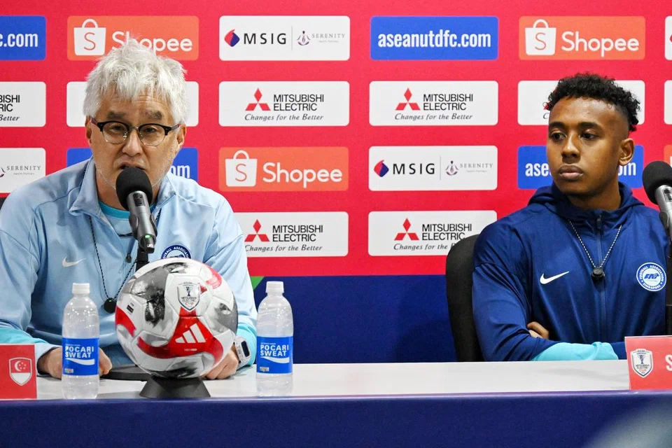 Jurulatih Singapura, Tsutomu Ogura (kiri), gembira anak didiknya sedang menunjukkan peningkatan di atas padang. Turut bersama beliau ialah penyerang Singa, Abdul Rasaq Akeem di sidang media di Stadium Jalan Besar pada 25 Disember. 