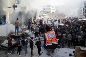 Penduduk Palestin memeriksa kerosakan akibat pengeboman Israel terhadap sebuah sekolah yang menempatkan pelarian di Bandar Gaza, pada 14 November.