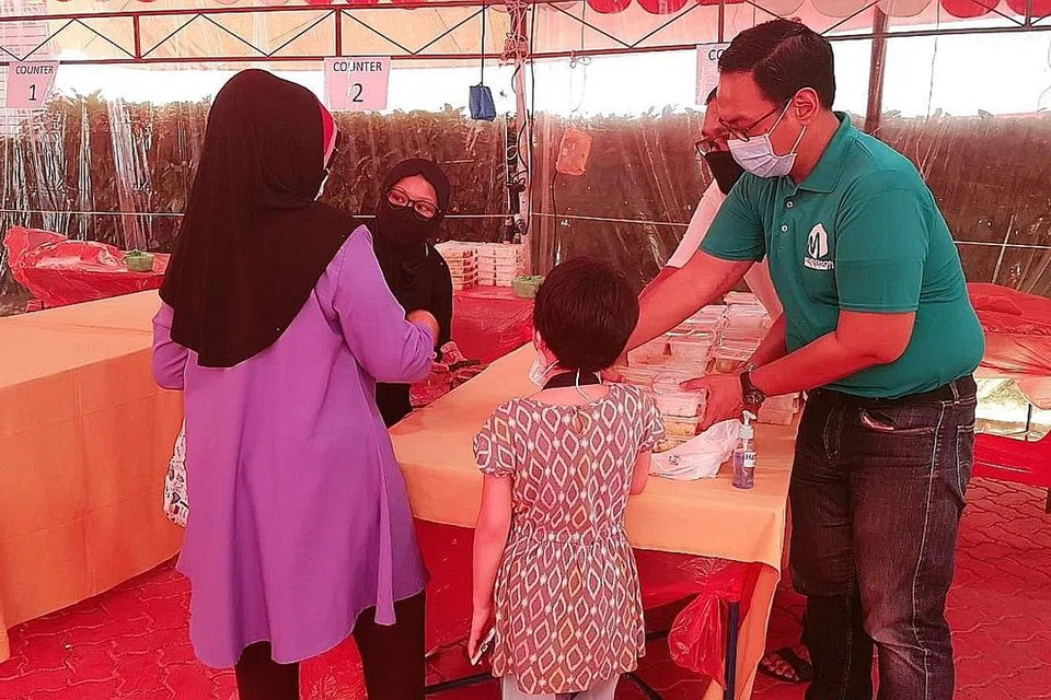 HULUR BANTUAN: Encik Sudirman (paling kanan, baju hijau) mengagihkan paket makanan kepada penerima manfaat inisiatif #SGUnited Buka Puasa di Kelab Masyarakat Henderson. - Foto KELAB MASYARAKAT HENDERSON